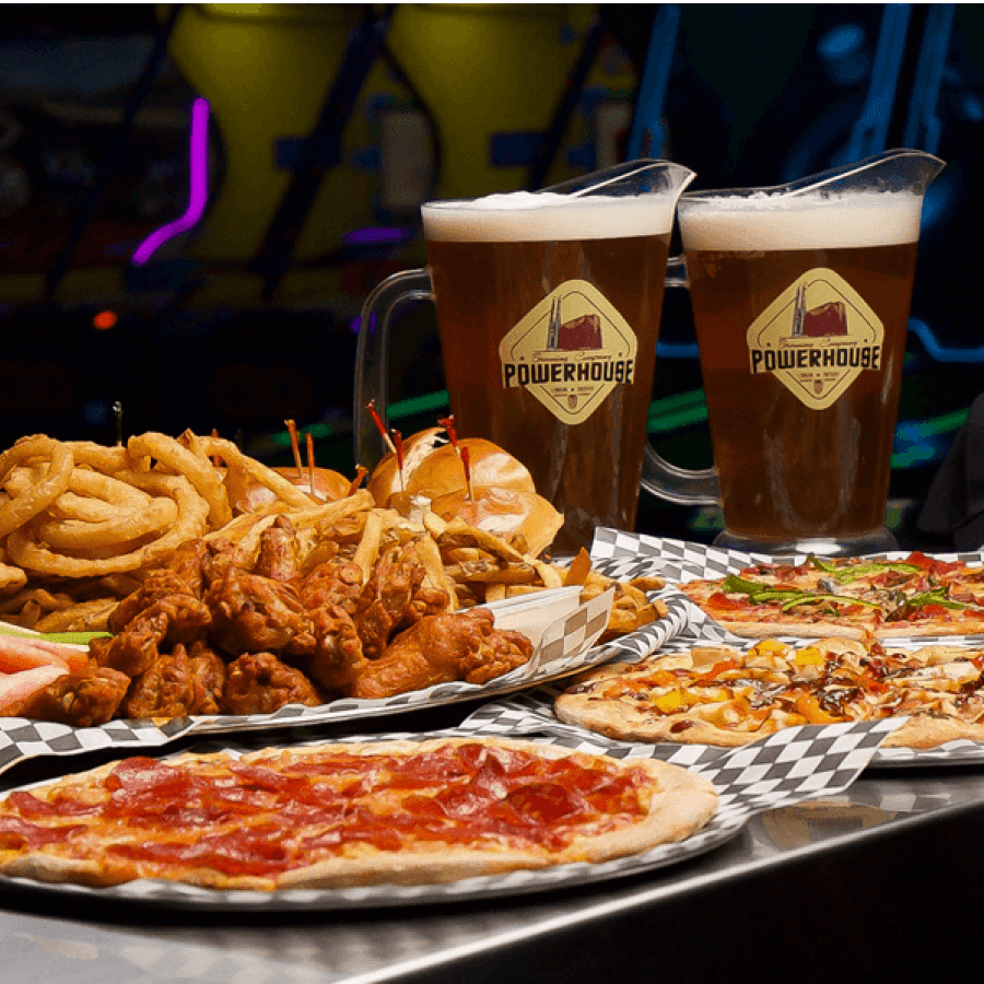 Party catering spread with pizza, chicken wings, and pitchers of beer